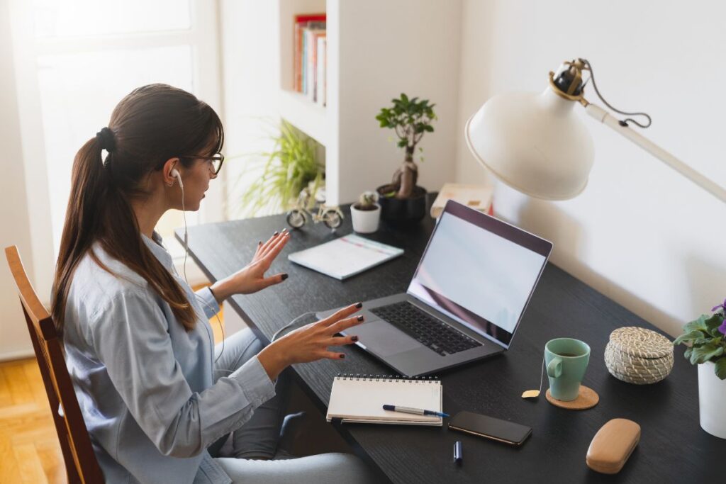 Woman on a video call while working from a tidy home office desk, representing beginner-friendly remote jobs like content moderator or virtual assistant.