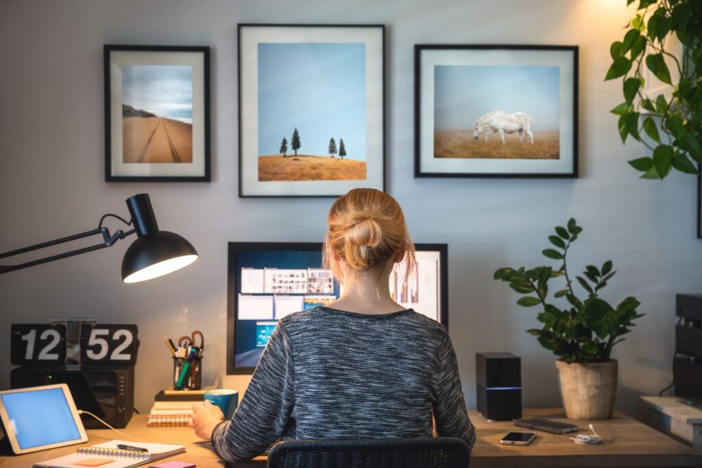 Woman working remotely at a home office desk with dual monitors, tablet, and coffee, showing a modern setup for remote jobs for beginners and online work.